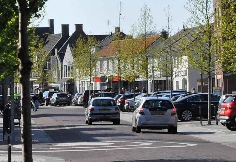leefomgeving verkeer en vervoer, auto's, voetgangers en fietsers in winkelstraat met parkeerstroken
